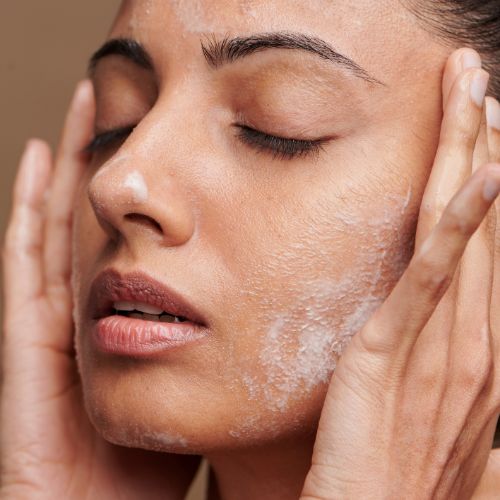 women washing face with cleanser