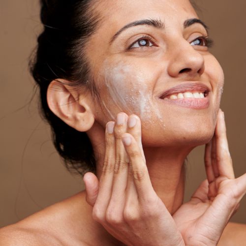 women washing face with cleanser